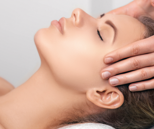 A woman receiving Reiki healing in a calming environment at Reflexology and Reiki Warwickshire, Kenilworth, Leamington Spa, Warwick, Stratford-upon-Avon. The practitioner, Jayne Amanda, is gently placing her hands over the woman's head.