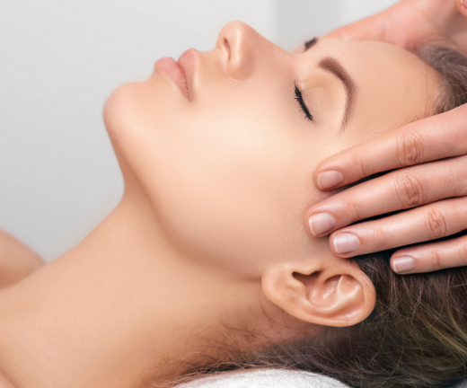 A woman receiving Reiki healing in a calming environment at Reflexology and Reiki Warwickshire, Kenilworth, Leamington Spa, Warwick, Stratford-upon-Avon. The practitioner, Jayne Amanda, is gently placing her hands over the woman's head.