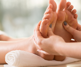 A therapist performing a reflexology and Reiki session, applying pressure to the sole of the foot.