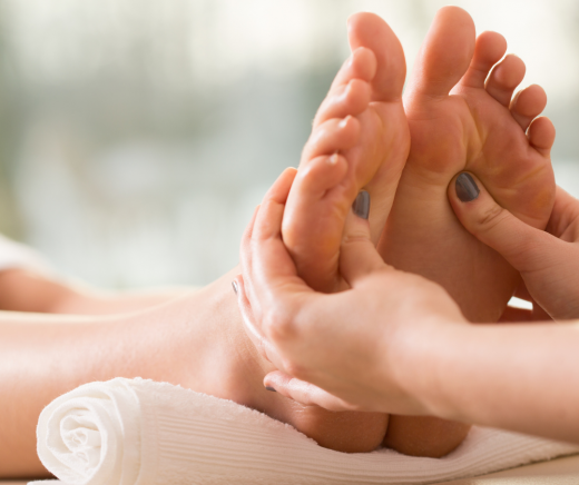 A therapist performing a reflexology and Reiki session, applying pressure to the sole of the foot.