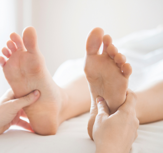 A therapist performing a reflexology and Reiki session, applying pressure to the sole of the foot.