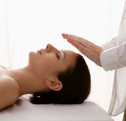 A woman receiving Reiki healing in a calming environment at Reflexology and Reiki Warwickshire, Leamington Spa, Warwick, Stratford-upon-Avon. The practitioner, Jayne Amanda, is gently placing her hands over the woman's head.